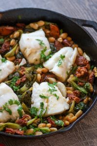 One Pan Chorizo and Cod is an easy and flavorful weeknight meal. Cod, escarole, and white beans get a punch of flavor from spicy, garlicky chorizo. This one pan dish has only 7 ingredients and takes just 30 minutes to prepare, and just as perfect for guests as it is for weeknights.