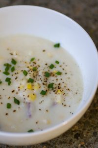 white bowl of corn chowder with chives